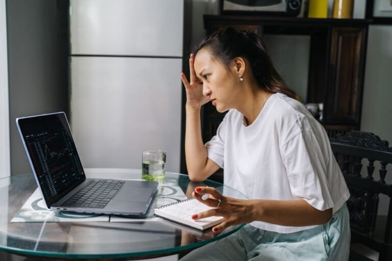 Worried person looking at a declining stock chart on a laptop screen, representing the fear of investing in the stock market