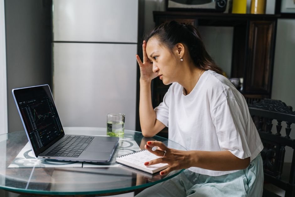 Worried person looking at a declining stock chart on a laptop screen, representing the fear of investing in the stock market