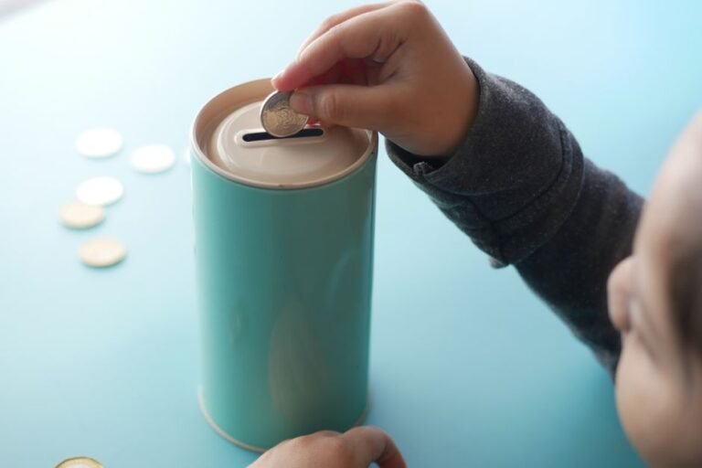 Young child learning about money and investing with euro coins and a savings jar at home