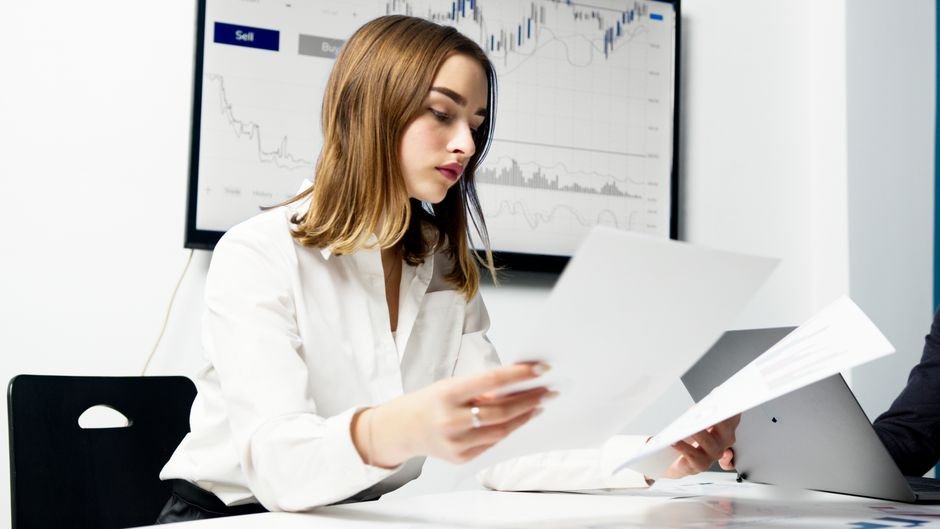 Person comparing crypto and ETF performance charts side by side on a desk