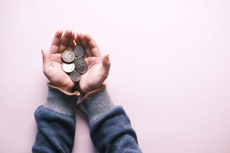 Person counting small euro coins on a wooden table, considering micro-investing opportunities in Europe